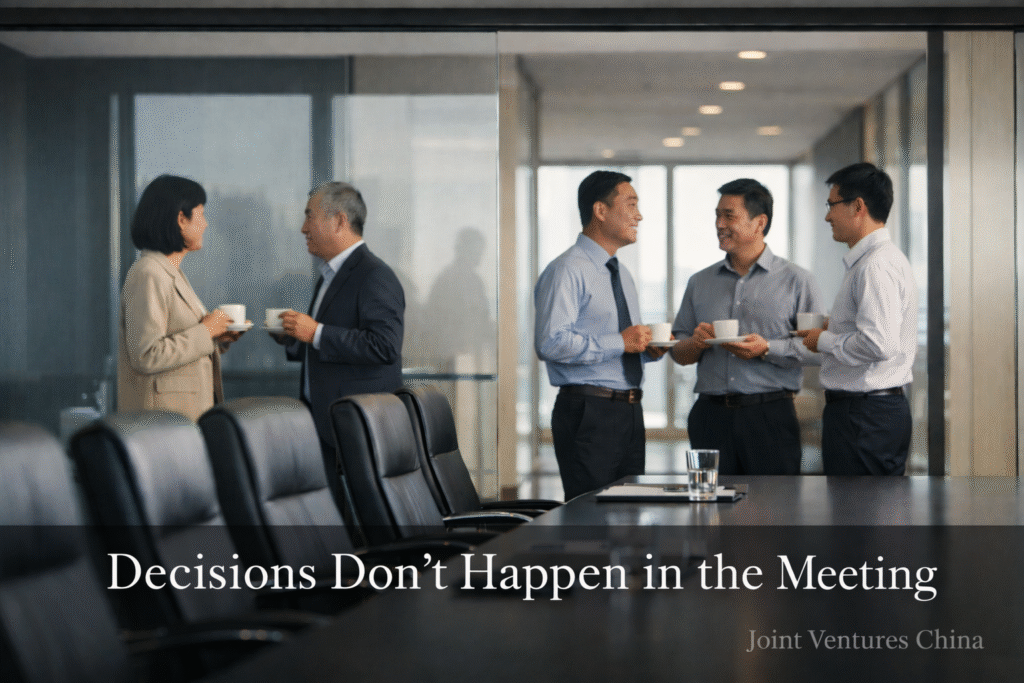 decision making in China illustrated by an empty conference room while executives talk and align in the hallway
